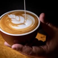 Close-up of a latte with leaf latte art held in a hand
