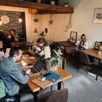 Guests working and chatting at wooden tables inside the café
