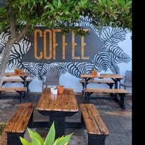 Garden courtyard with wooden benches and a hand-painted COFFEE mural